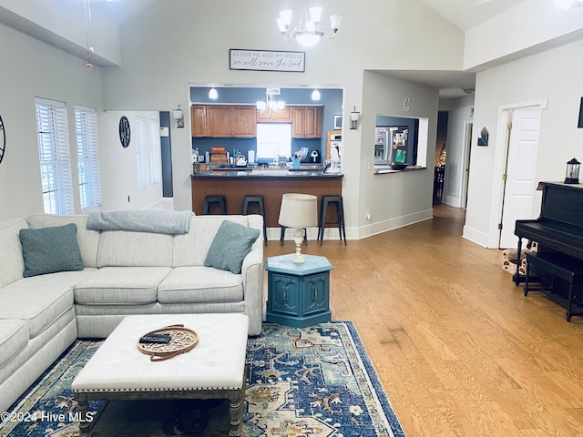 living room with a chandelier, high vaulted ceiling, and light hardwood / wood-style flooring