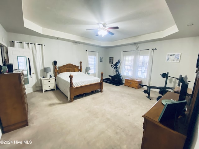 carpeted bedroom with a tray ceiling and ceiling fan