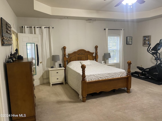 carpeted bedroom featuring a tray ceiling and ceiling fan