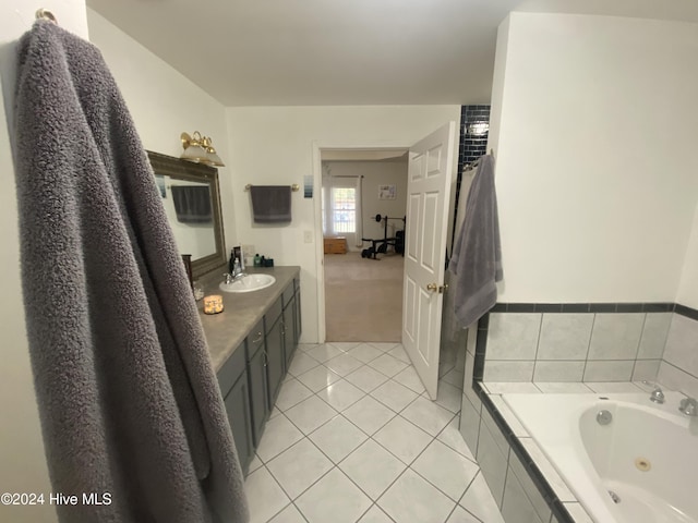 bathroom with tile patterned floors, vanity, and a relaxing tiled tub