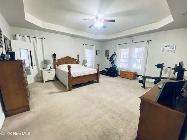 carpeted bedroom with ceiling fan and a raised ceiling