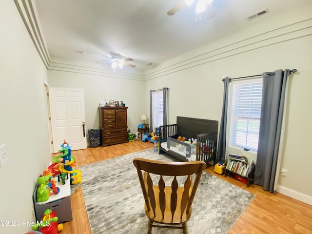 sitting room with light hardwood / wood-style floors, ceiling fan, and crown molding