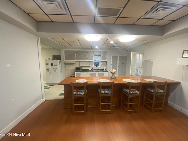 interior space featuring gray cabinetry, sink, wood counters, white refrigerator with ice dispenser, and wood-type flooring