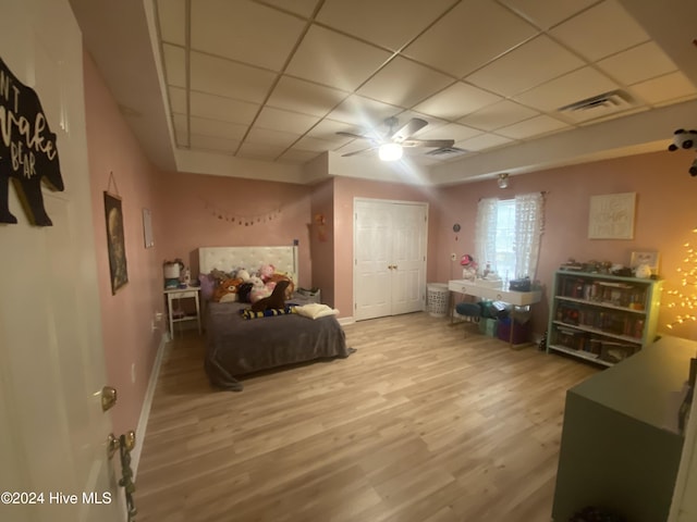 bedroom featuring a paneled ceiling, ceiling fan, wood-type flooring, and a closet