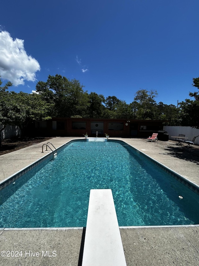 view of pool with a patio area and a diving board