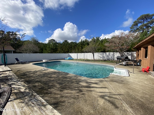 view of swimming pool featuring a diving board and a patio