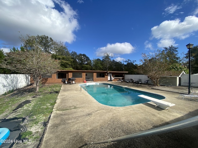 view of swimming pool with a diving board and a patio area