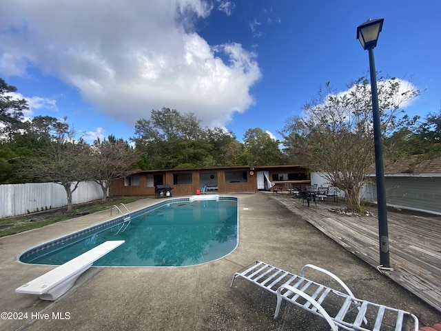 view of pool with a diving board and a deck