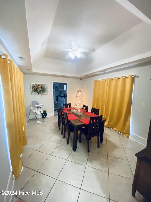 dining room featuring a raised ceiling, ceiling fan, and light tile patterned flooring