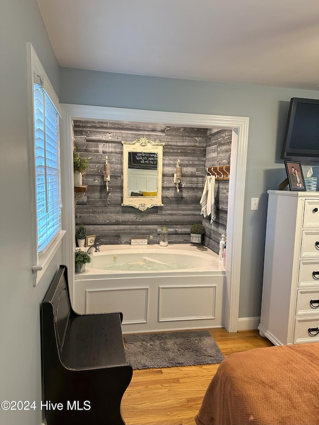 bathroom featuring hardwood / wood-style floors, a tub to relax in, and wooden walls