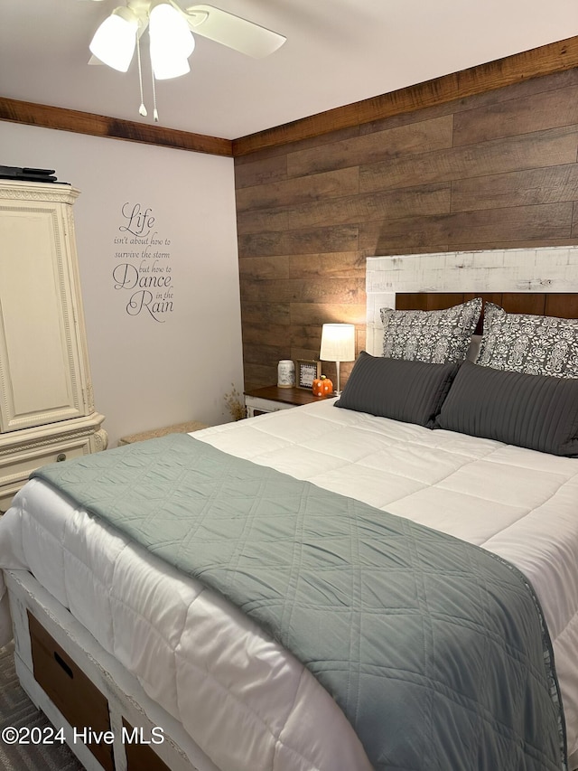 bedroom featuring ceiling fan and wood walls
