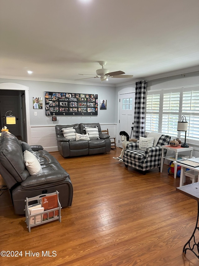 living room with wood-type flooring, ceiling fan, and ornamental molding