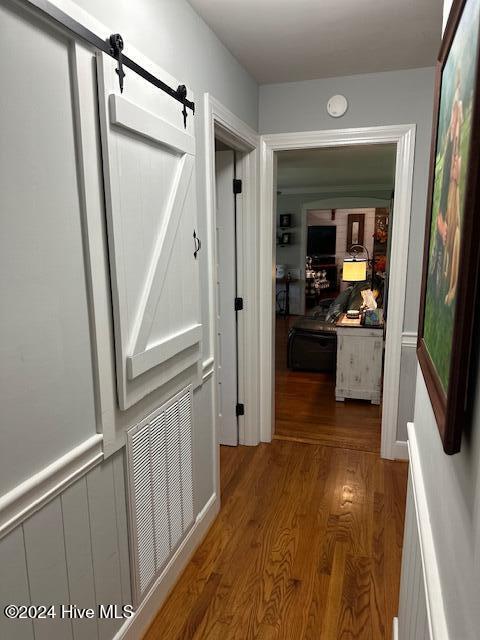 hallway with a barn door and hardwood / wood-style floors