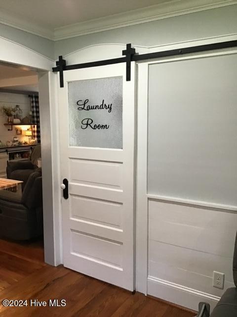 doorway to outside featuring a barn door, dark wood-type flooring, and ornamental molding