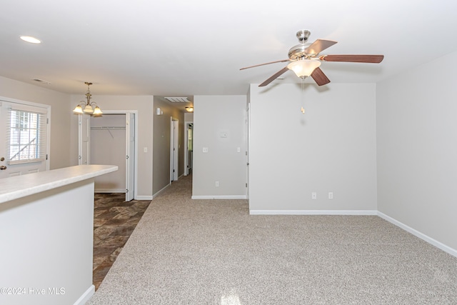 interior space featuring ceiling fan with notable chandelier and dark carpet