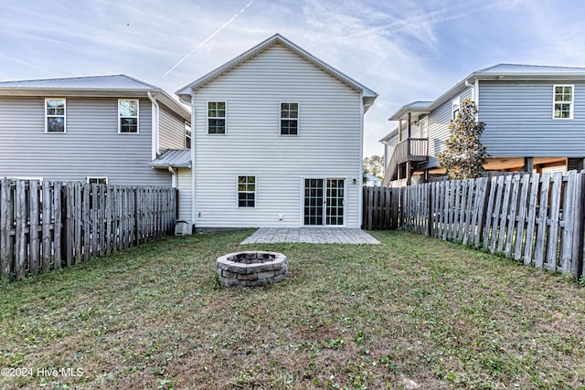 rear view of property featuring a patio, a yard, and an outdoor fire pit