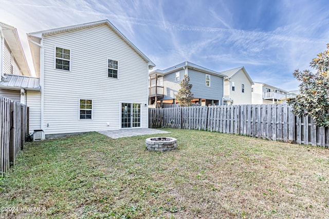 back of house featuring a patio area, a yard, and a fire pit