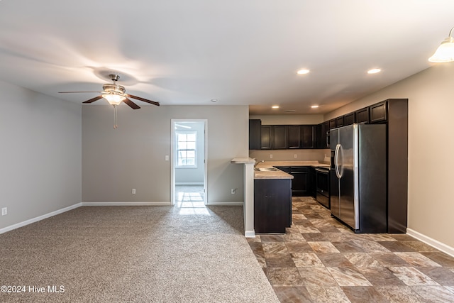 kitchen with appliances with stainless steel finishes, dark brown cabinetry, sink, light colored carpet, and ceiling fan