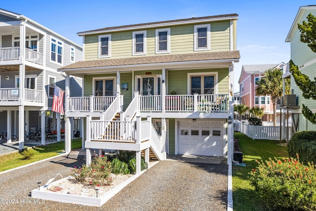 view of front of property featuring covered porch, a garage, a front lawn, and central air condition unit