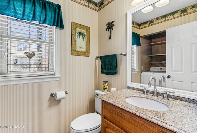 bathroom featuring toilet, vanity, and washer / dryer