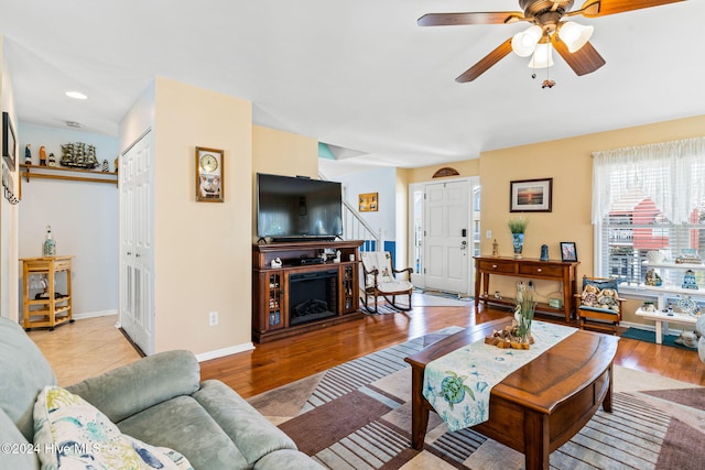 living room with a fireplace, light hardwood / wood-style flooring, and ceiling fan