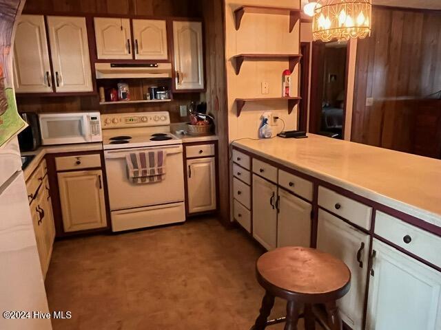 138 NW 17th St, Oak Island, NC 28465 - kitchen with white appliances, open shelves, a chandelier, under cabinet range hood, and light countertops