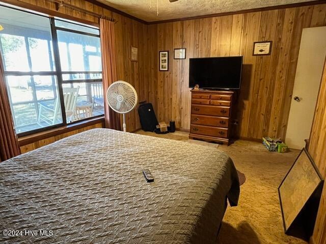 bedroom featuring wooden walls, ornamental molding, and carpet floors