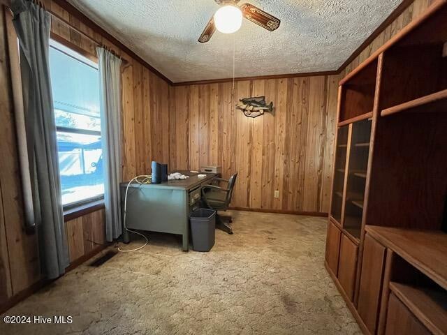 office area with carpet, wood walls, a textured ceiling, and ceiling fan