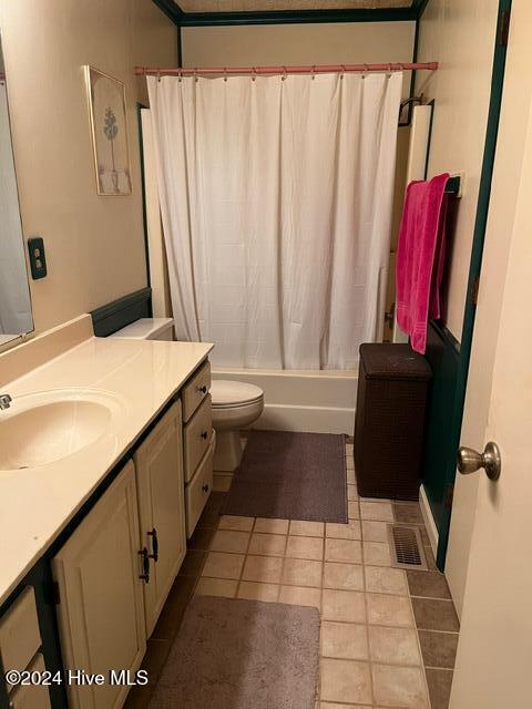 full bathroom featuring vanity, shower / bath combo with shower curtain, tile patterned floors, and toilet