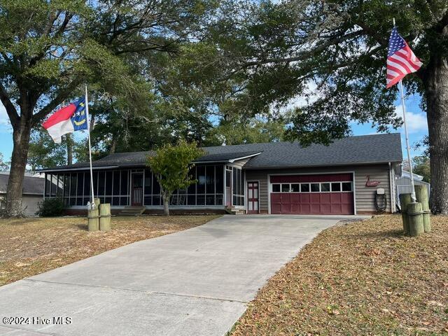 138 NW 17th St, Oak Island, NC 28465 - ranch-style house featuring a sunroom, a garage, and driveway