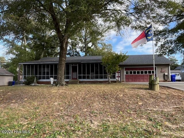 138 NW 17th St, Oak Island, NC 28465 - ranch-style home with a sunroom, an attached garage, and concrete driveway