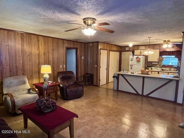 138 NW 17th St, Oak Island, NC 28465 - living area featuring ceiling fan, a textured ceiling, wooden walls, and light flooring