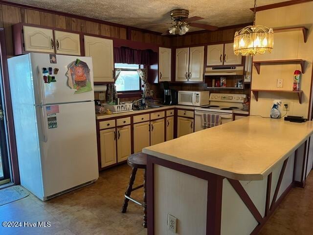 kitchen featuring a textured ceiling, kitchen peninsula, a breakfast bar area, and white appliances