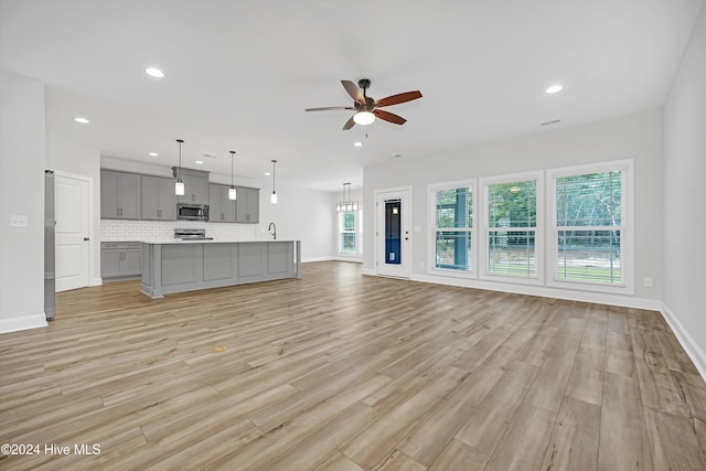 unfurnished living room featuring ceiling fan, light hardwood / wood-style floors, and sink