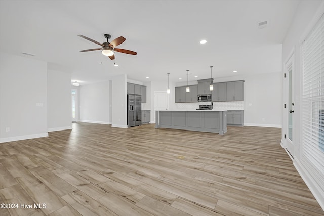 unfurnished living room featuring ceiling fan and light hardwood / wood-style floors