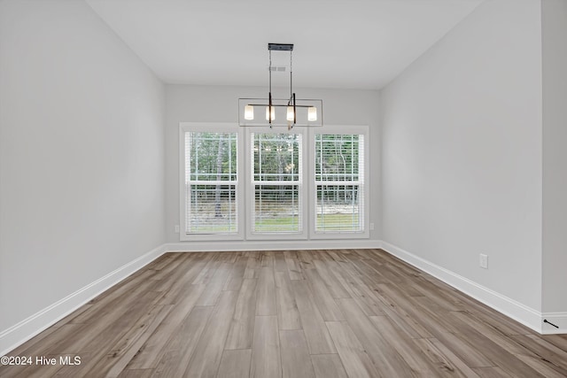 unfurnished dining area featuring light wood-type flooring and a chandelier