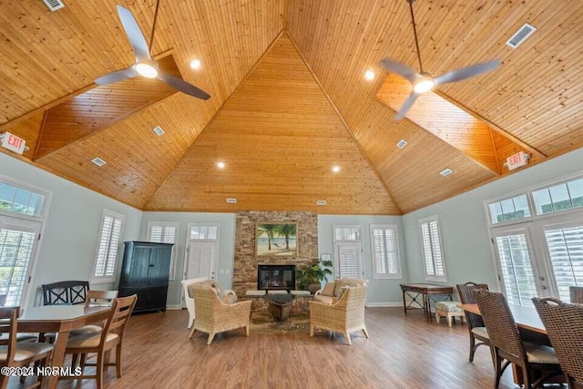 living room featuring ceiling fan, wood-type flooring, wood ceiling, and a towering ceiling