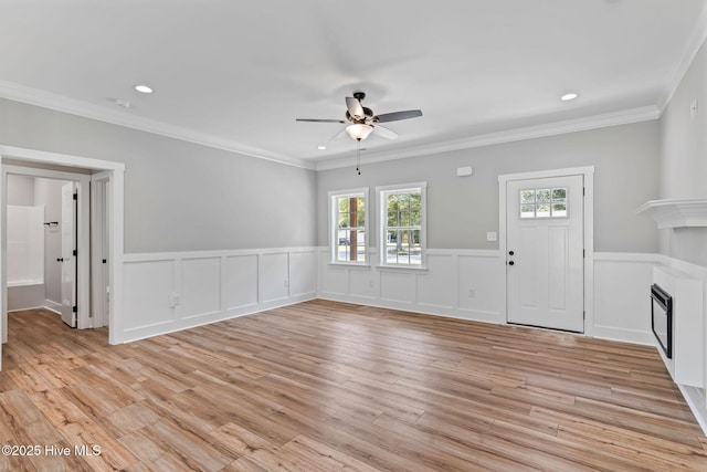 2013 E Hawthorne St, Goldsboro, NC 27530 - unfurnished living room featuring ceiling fan, a fireplace, light wood-style flooring, wainscoting, and crown molding