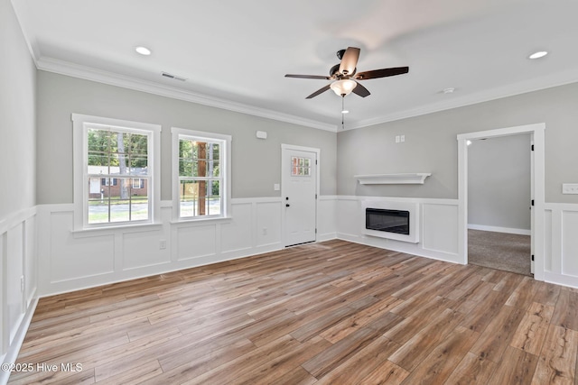 2013 E Hawthorne St, Goldsboro, NC 27530 - unfurnished living room with light wood finished floors, a ceiling fan, a glass covered fireplace, wainscoting, and crown molding