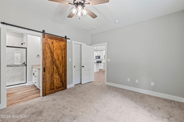 2013 E Hawthorne St, Goldsboro, NC 27530 - unfurnished bedroom featuring light carpet, a barn door, baseboards, ensuite bathroom, and ceiling fan