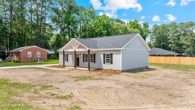 2013 E Hawthorne St, Goldsboro, NC 27530 - modern farmhouse featuring view of wooded area, a porch, dirt driveway, and a shingled roof