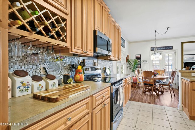 kitchen with pendant lighting, backsplash, ornamental molding, appliances with stainless steel finishes, and light hardwood / wood-style floors