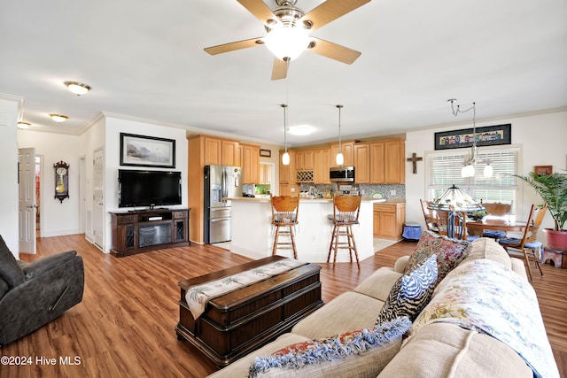 living room featuring ceiling fan, ornamental molding, and light wood-type flooring