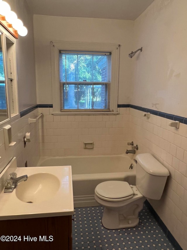 bathroom featuring tile patterned floors, toilet, tile walls, a washtub, and vanity