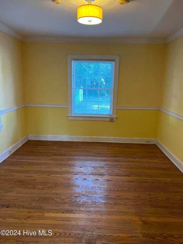 spare room featuring dark wood-type flooring and ornamental molding