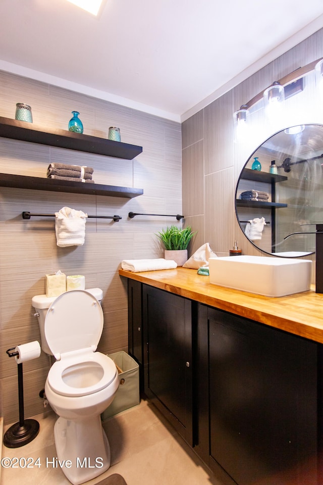 bathroom with vanity, toilet, and tile walls