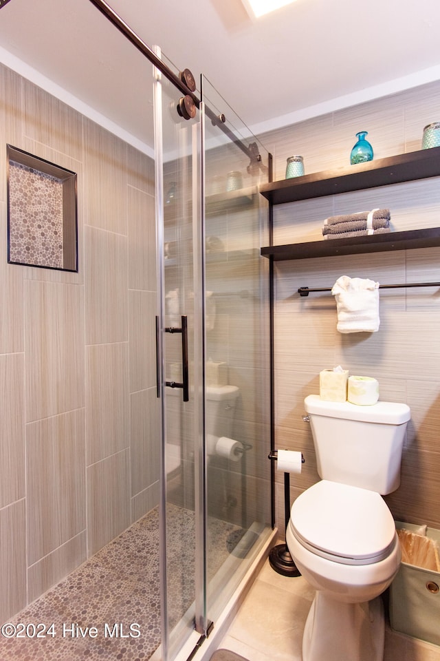 bathroom featuring walk in shower, toilet, and tile walls