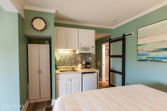 bedroom featuring ornamental molding, light hardwood / wood-style flooring, a barn door, and sink