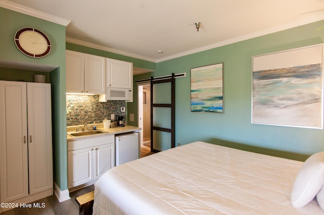 bedroom featuring hardwood / wood-style flooring, ornamental molding, a barn door, and sink