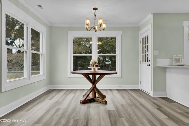 unfurnished dining area with an inviting chandelier, crown molding, and light wood-type flooring